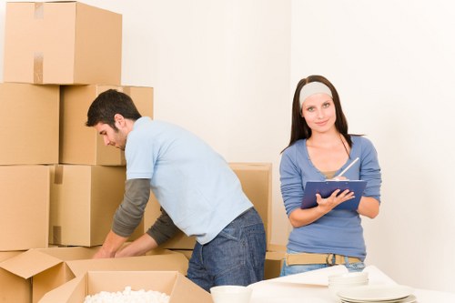 Professional movers carrying furniture through a narrow staircase in Hammersmith